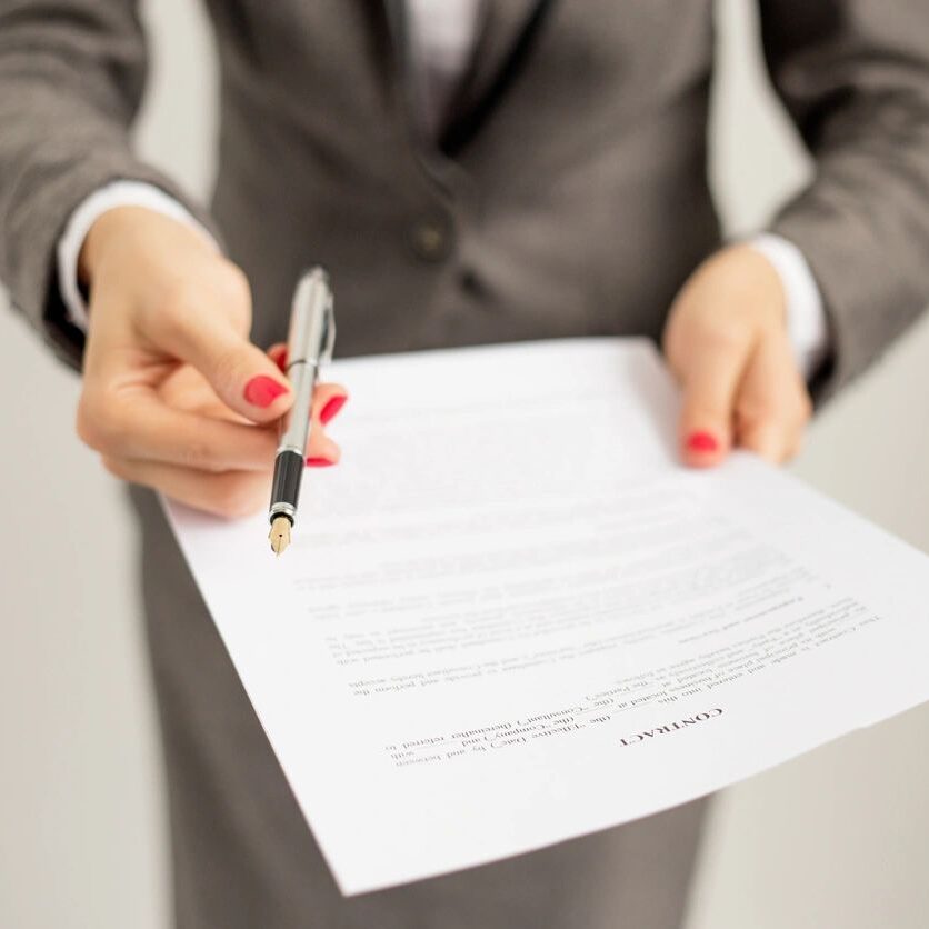 A person in a suit holding a pen and paper